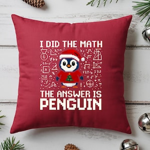 Peut inclure: Un coussin carré rouge avec le texte "I DID THE MATH THE ANSWER IS PENGUIN" en lettres blanches. Un pingouin pixélisé portant un bonnet de Père Noël et un pull rouge avec un sapin de Noël vert est au centre.