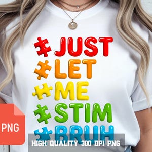 Puede incluir: Camiseta blanca con la frase "JUST LET ME STIM BRUH" en letras coloridas con forma de piezas de rompecabezas. El diseño incluye colores vibrantes. La camiseta tiene cuello redondo y mangas cortas.