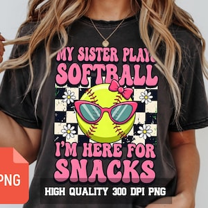 Pode incluir: Camiseta preta com um gráfico de softball. O softball tem óculos de sol rosa e um laço. O texto diz "MY SISTER PLAY SOFTBALL I'M HERE FOR SNACKS". A camisa também tem o texto "HIGH QUALITY 300 DPI PNG".