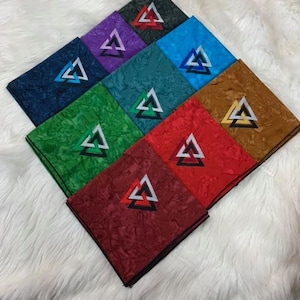 Puede incluir: Nueve cuadrados de tela con un patrón geométrico de tres triángulos superpuestos en el centro. Los cuadrados son de diferentes colores: azul marino, verde azulado, morado, verde, rojo, naranja, marrón, azul claro y rojo oscuro.