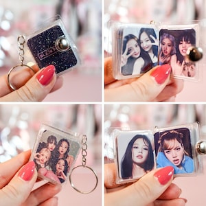 May include: Clear plastic keychain with a silver keyring. The keychain features a small, square, hinged case with photos of a musical group. One keychain has a black glitter background with the text "BLACKPINK".