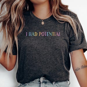 May include: A white ceramic mug with a black handle and the text "But First, Coffee" in a handwritten style. The mug is on a white surface. The mug is approximately 4 inches tall.