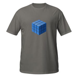 May include: A gray t-shirt featuring a blue Rubik's Cube design. The cube is rendered in a 3D style, with each square a different shade of blue. The shirt has short sleeves and a crew neck.
