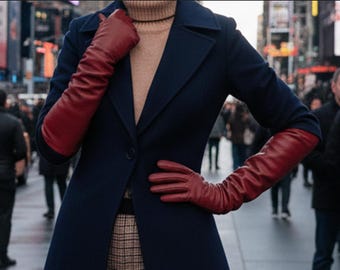 May include: A person wearing a navy blue coat and long, red leather gloves. The coat is buttoned and the person is standing in a city setting. The gloves extend past the elbows.