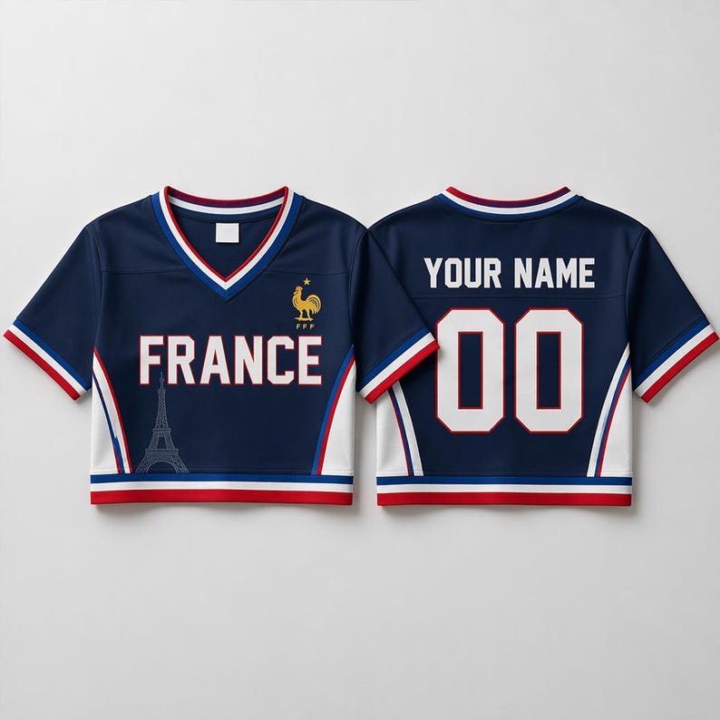 May include: Navy blue crop top jersey with white and red trim. The front displays "FRANCE" and an Eiffel Tower graphic. The back has "YOUR NAME" and the number "00". A golden rooster emblem is on the front.