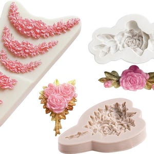 May include: An assortment of silicone molds and decorative elements featuring floral designs. The molds are in various shapes, including a rose, a bouquet, and decorative borders. The colors are primarily pink and white, with gold accents.
