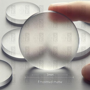 May include: A collection of clear, frosted matte glass circles, one being held by a finger. The circles are 3mm thick. The text "Frrosttted matte" is visible. The background is light grey.