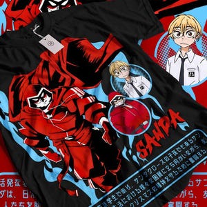 Könnte beinhalten: Schwarzes T-Shirt mit einer rot-schwarzen Grafik im Anime-Stil eines Charakters in einem Santa Claus-ähnlichen Outfit. Das Design enthält blaue flammenartige Akzente und japanischen Text. Zwei zusätzliche Charakterporträts sind ebenfalls sichtbar.