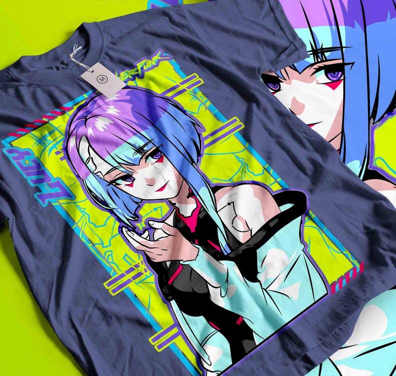 May include: A navy blue t-shirt featuring a vibrant anime-style illustration of a female character with blue and purple hair. The design includes the word "LUCY" and other text in a neon green and blue color scheme. The shirt has a tag attached.