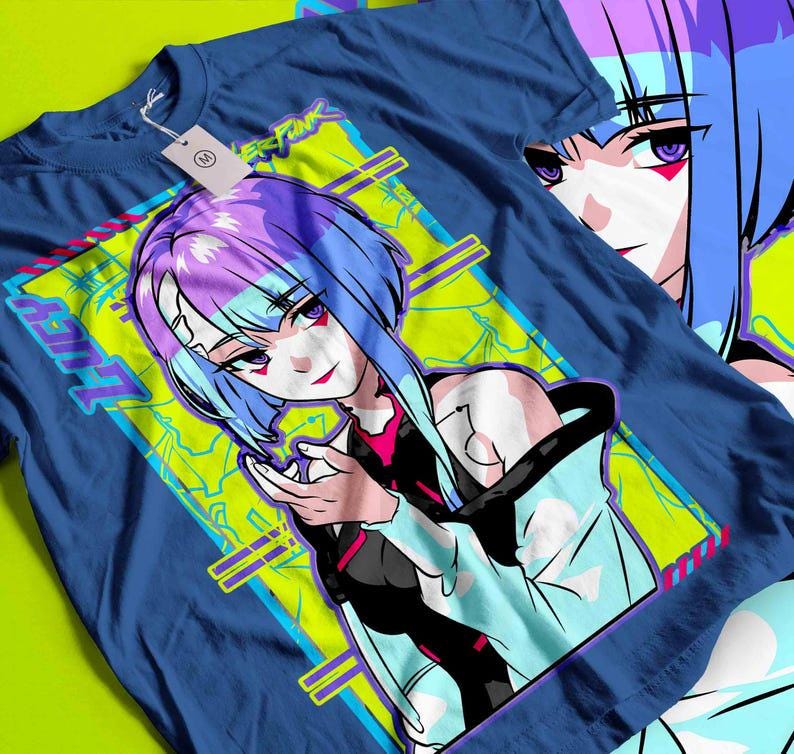 May include: A blue t-shirt featuring a vibrant anime-style illustration. The graphic showcases a female character with blue and purple hair, set against a neon green and yellow background. The word "LUCY" is visible on the design, along with the text "CYBERPUNK".