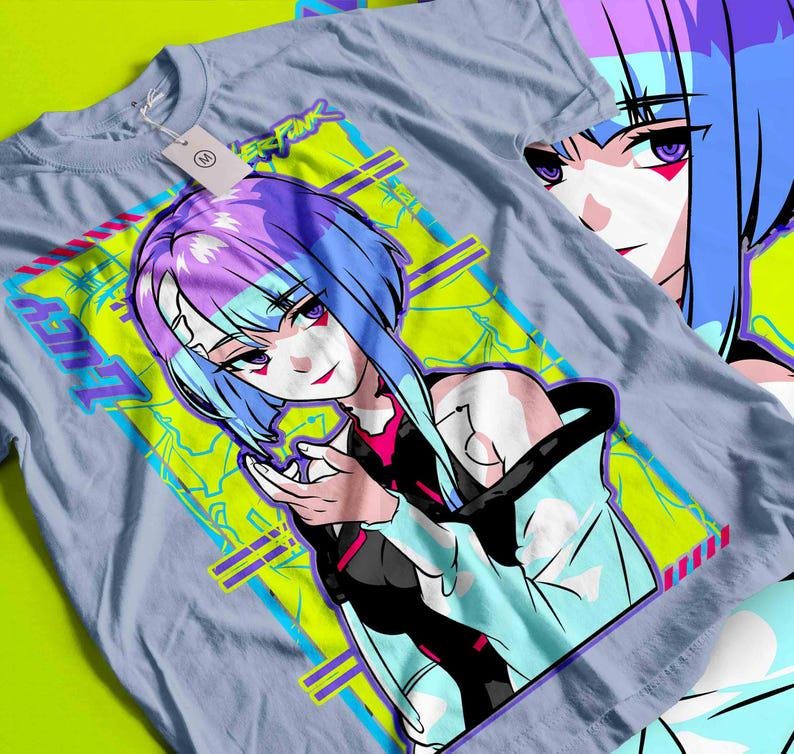 May include: A light blue t-shirt featuring a vibrant anime-style illustration of a female character with blue and purple hair. The design includes the text "LUCY" and "CYBERPUNK" in a neon green and blue color scheme.