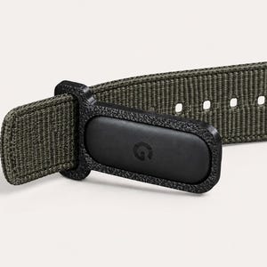 May include: An olive green woven nylon watch strap featuring a black textured plastic connector piece. The connector has a small, embossed letter G logo on its surface. The strap includes a series of evenly spaced adjustment holes for sizing.