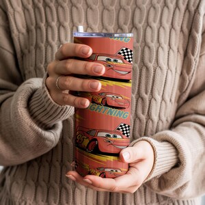 May include: A red tumbler featuring the character Lightning McQueen from the Cars movie. The design includes the number 95, checkered flags, and the word "Lightning". The tumbler has a silver lid and a white straw.