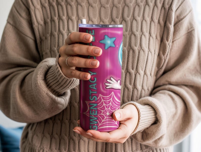 May include: A tall, cylindrical tumbler with a pink and purple gradient design. The tumbler features the name "GWEN STACY" in teal, along with cartoon graphics of a star, a hand, and a spiderweb. It has a silver lid and a white straw.