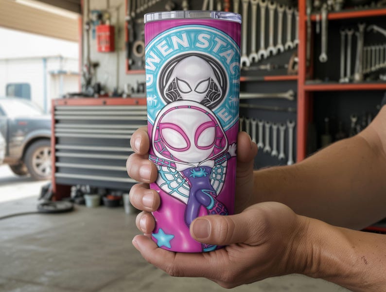 May include: A pink and teal tumbler featuring a Gwen Stacy Spider-Woman design. The tumbler has a white and pink illustration of the character, with the words "GWEN STACY" in a circular teal design. The tumbler is held in a person's hands.