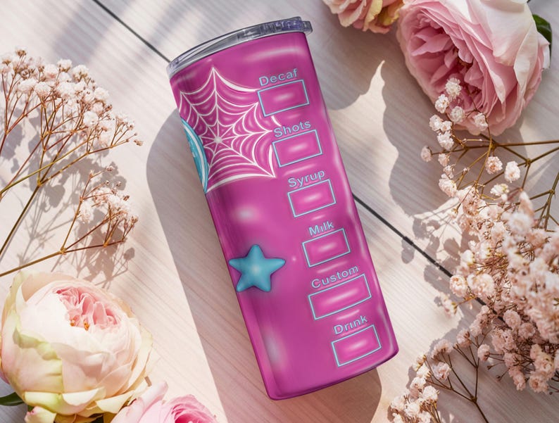 May include: A pink tumbler with a spiderweb design and a blue star. The tumbler has labels for drink customization, including "Decaf," "Shots," "Syrup," "Milk," "Custom," and "Drink." The tumbler is surrounded by pink roses and white flowers.