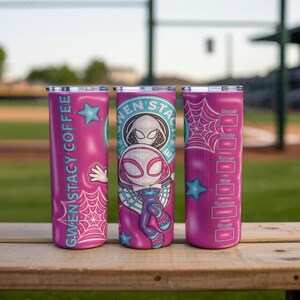 May include: Three pink stainless steel tumblers with Gwen Stacy Spider-Woman designs. One tumbler has the text "Gwen Stacy Coffee" and a hand graphic. Another features the Spider-Woman logo. The third has a coffee recipe chart.