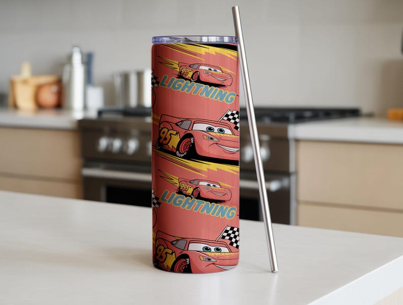 May include: A red tumbler featuring a repeating pattern of Lightning McQueen from the Cars movie. The design includes the number 95, a checkered flag, and the word "Lightning". A silver metal straw is next to the tumbler.