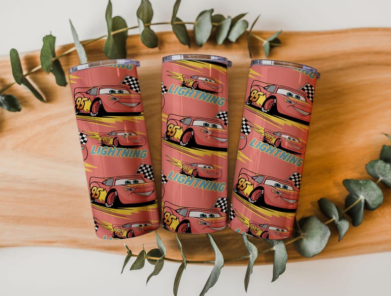 May include: Three red tumblers with a repeating pattern of the character Lightning McQueen from the movie Cars. The design includes the number 95, a checkered flag, and the word "LIGHTNING" in a yellow font. The tumblers are cylindrical and have a silver rim.