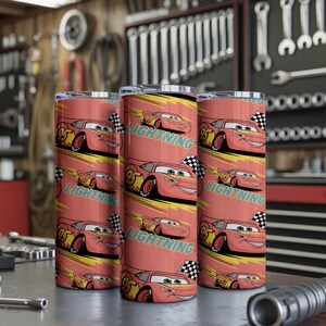 May include: Three red insulated tumblers featuring a cartoon race car design. The design includes the number 95, a checkered flag, and the word "LIGHTNING" in teal. The tumblers are cylindrical and appear to be made of stainless steel.