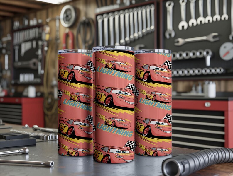 May include: Three red insulated tumblers featuring a cartoon race car design. The design includes the number 95, a checkered flag, and the word "LIGHTNING" in teal. The tumblers are cylindrical and appear to be made of stainless steel.