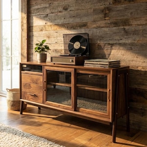 May include: A wooden media console featuring a left-side cabinet with three drawers and a right-side section with two glass sliding doors. A record player with a black vinyl record and a stack of records sit on top of the console surface.