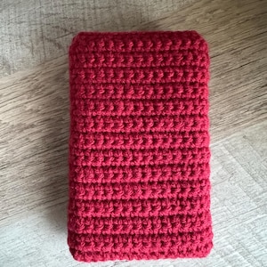 K&ouml;nnte beinhalten: Eine rote rechteckige H&auml;kel-Tasche oder -H&uuml;lle. Die Tasche ist mit einem einfachen Stichmuster gearbeitet und hat eine glatte, gleichm&auml;&szlig;ige Textur.