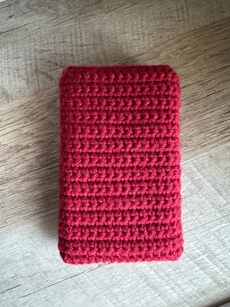 May include: A red crocheted rectangular pouch or case. The pouch is made with a simple stitch pattern and has a smooth, even texture.