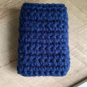 May include: A dark blue crocheted pouch or case. The pouch is made with a textured stitch and has a rectangular shape.