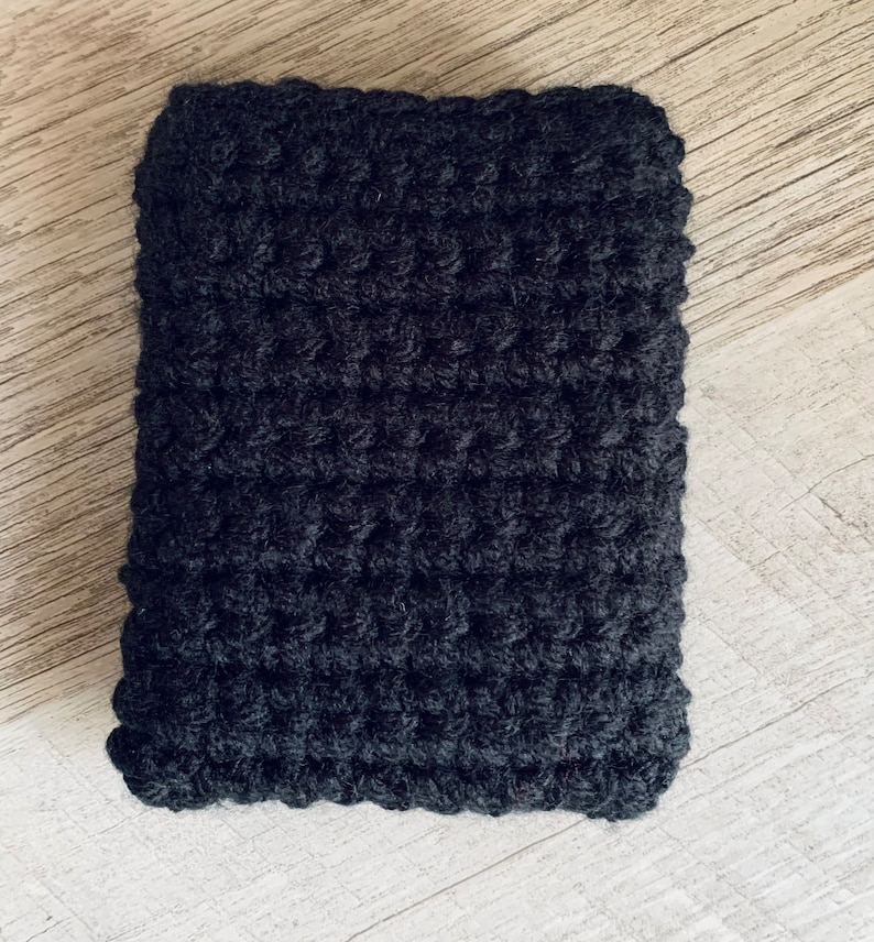 K&ouml;nnte beinhalten: Ein quadratisches H&auml;kelst&uuml;ck in Schwarz mit einer strukturierten Oberfl&auml;che.