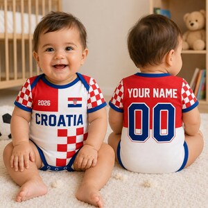 May include: A baby bodysuit featuring a red and white checkered pattern, the text CROATIA, the number 2026, and a Croatian flag on the front. The back displays the text YOUR NAME above the number 00, with blue trim on the sleeves and neckline.