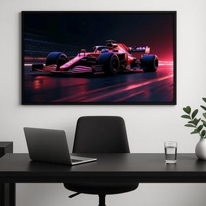 Puede incluir: Impresión enmarcada de un coche de carreras de Fórmula 1 en movimiento. El coche es principalmente rojo con detalles en negro, corriendo por una pista con un fondo borroso rojo y negro. La imagen está en un entorno oscuro.