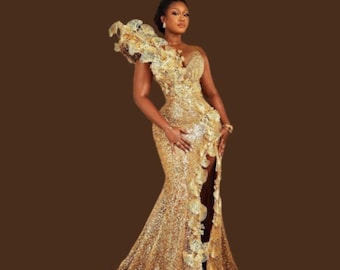 May include: A glamorous, floor-length gold sequin gown with a high slit and a dramatic, ruffled shoulder detail. The dress features a fitted bodice and a flowing skirt, perfect for formal events.