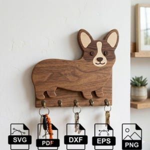 May include: A wooden key holder in the shape of a corgi dog, with a light and dark brown finish. It features five brass hooks for keys and is mounted on a white wall. Keys are hanging from the hooks. The key holder is a decorative item.
