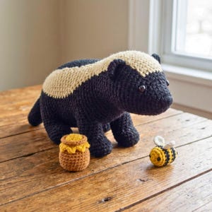 May include: A white ceramic mug with a black handle and the text "But First, Coffee" in a black, bold font. The mug is on a wooden surface. The mug is approximately 10 cm tall.