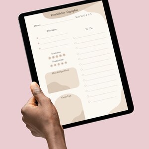 Könnte beinhalten: Ein digitales Tablet mit einem Tagesplaner mit dem Titel "Persönlicher Tagesplan". Der Planer enthält Abschnitte für Datum, Prioritäten, To-Do-Liste, Motivation, Produktivität und eine Zusammenfassung. Das Design ist minimalistisch mit beige- und braunen Akzenten.