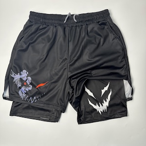 Puede incluir: Pantalones cortos deportivos negros con cintura con cordón y bolsillos laterales. Los pantalones cortos presentan un gráfico blanco y morado en la pierna izquierda y un gráfico blanco en la pierna derecha. Hecho de material brillante y liso.