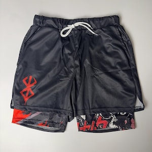 May include: Black athletic shorts with a red graphic on the left leg and a white drawstring. The shorts have a mesh outer layer and a patterned inner layer with red and black designs. The shorts are designed for athletic activities.