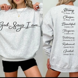 May include: Light gray sweatshirt with the text "God Says I am..." on the front. The back of the sweatshirt features a list of words including "Strong", "Chosen", and "Beautiful".