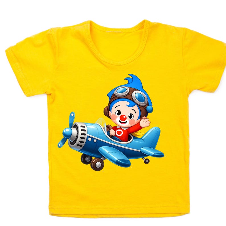 Puede incluir: Camiseta amarilla de manga corta con una ilustraci&oacute;n de dibujos animados de un personaje en un avi&oacute;n azul. El personaje tiene pelo azul, gafas y una camisa roja. El avi&oacute;n es azul con una h&eacute;lice.