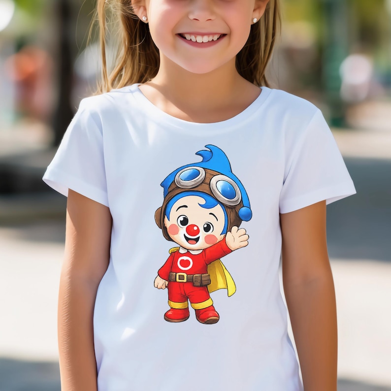 Puede incluir: Camiseta blanca con un personaje de dibujos animados. El personaje tiene pelo azul, gafas y un traje rojo. El personaje est&aacute; saludando. La camiseta es de cuello redondo.