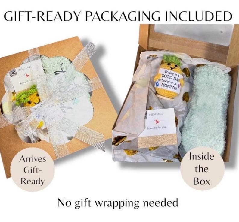 May include: Two gift boxes, one open, showcasing gift-ready packaging. The open box reveals a crocheted pineapple with a tag reading "Today is a GOOD DAY to become a MOMMY!" and a light green item. The other box is tied with a white ribbon.