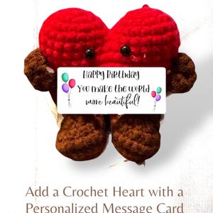 May include: A red crochet heart with brown arms and legs, featuring two black bead eyes. A white rectangular card is attached to the front with the text: Happy Birthday You make the world more beautiful! along with illustrations of colorful balloons.