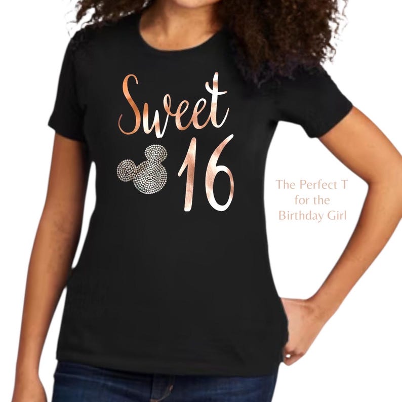 May include: A black short-sleeved t-shirt featuring the rose gold text Sweet 16. The design includes a mouse-ear silhouette filled with small silver-toned circular accents. The text The Perfect T for the Birthday Girl is printed on the right side.