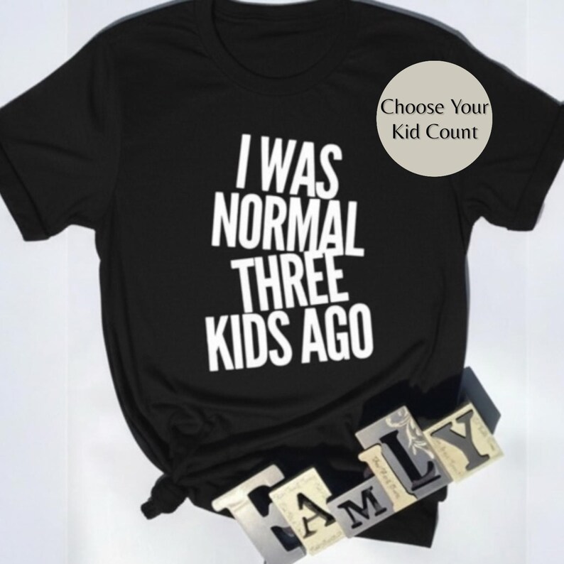 May include: Black t-shirt with the white text "I WAS NORMAL THREE KIDS AGO." A circular graphic in the upper right corner says "Choose Your Kid Count." The word "FAMILY" is spelled out in individual letter blocks at the bottom.
