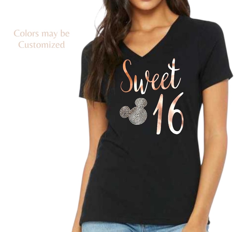 May include: A black V-neck t-shirt featuring the rose gold text Sweet 16 and a mouse-ear silhouette graphic filled with small circular patterns. The text Colors may be Customized is printed in the upper left corner of the garment.