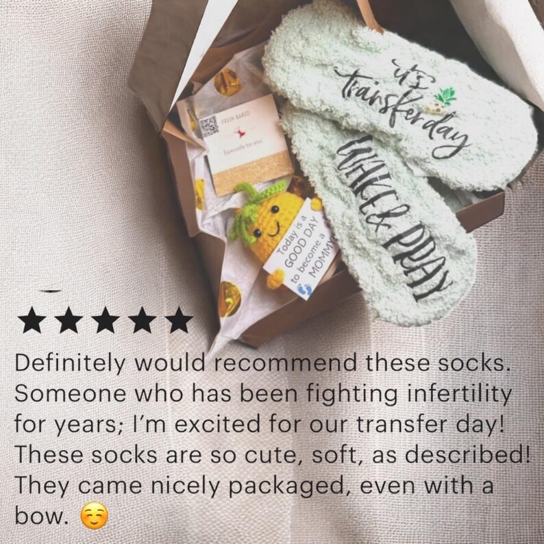 May include: A gift box containing a pair of light green fuzzy socks with the words "It's Transferday" and "Wake & Pray" printed on them. The box also includes a small crocheted pineapple and a card.