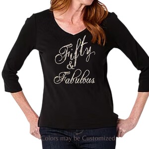 May include: Black V-neck shirt with three-quarter sleeves. The words "Fifty & Fabulous" are written in a cursive font with rhinestone embellishments. The text "Colors may be Customized" is at the bottom.
