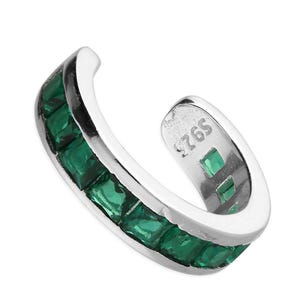 Puede incluir: Puño de oreja plateado con una fila de piedras preciosas verde esmeralda de corte cuadrado. El puño se curva alrededor de la oreja, con las piedras preciosas engastadas a lo largo del borde exterior. El interior del puño está estampado con "925".