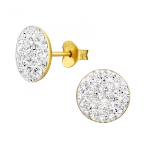 May include: A pair of gold-tone stud earrings featuring a circular face encrusted with numerous clear, faceted crystals. The earring post is clearly marked with the number 925, indicating sterling silver construction with a gold-tone finish.